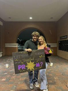 a man and woman holding a sign in front of a building