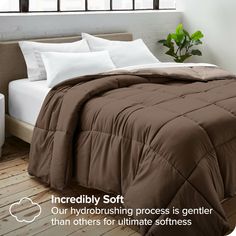 a bed with brown and white comforters in a room next to a window that reads incredibly soft our hydrobrushing process is greater than others for ultimate softness