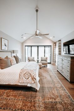 a large bed sitting in the middle of a living room next to a tv on top of a dresser