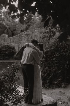 a man and woman embracing in front of a river