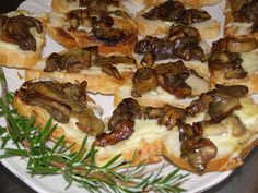 an assortment of appetizers on a white plate with green sprigs and rosemary