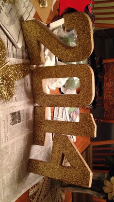 the letters are made out of wood and glittery paper on top of newspaper pages