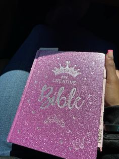 a person holding a pink book with writing on it that says, my creative bible