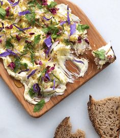 a wooden cutting board topped with bread and salad