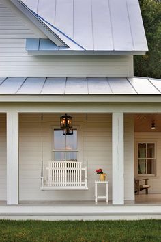 a white porch with a bench and lamp on it's front porch next to a house