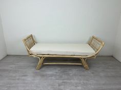 a bamboo bench with a cushion on it in a room that has white walls and wood flooring