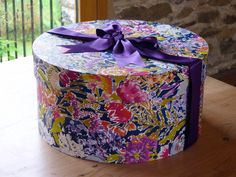 a colorful box with a purple bow on it sitting on top of a wooden table