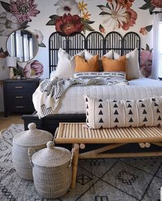 a bedroom with floral wallpaper and bedding in the corner, along with two wicker stools