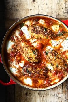 a red pan filled with food on top of a wooden table