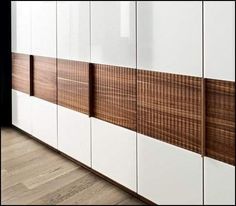 a white and brown cabinet with wooden panels on the wall next to a hardwood floor