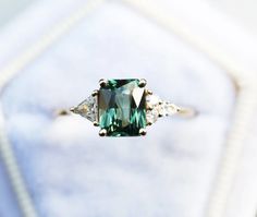 an emerald colored ring with three diamonds on it