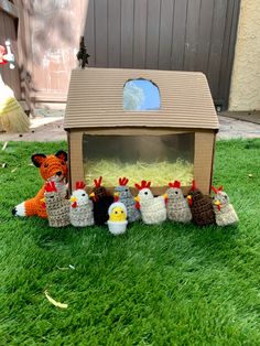 there is a small chicken family in front of a fake bird house on the grass