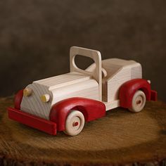 a wooden toy truck sitting on top of a piece of wood next to a tree stump