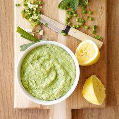 a wooden cutting board topped with a bowl of guacamole