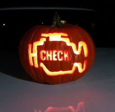 a carved pumpkin with the word check on it in front of a car at night