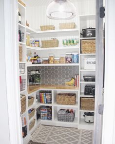 an organized pantry with white shelves and baskets on the bottom shelf, under a light fixture