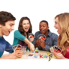 four people playing cards at a table with drinks and water in front of their faces