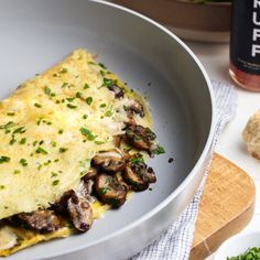 an omelet with mushrooms and parsley in a pan next to some bread