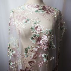 a white dress with pink and green flowers is on display in front of a mannequin