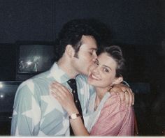 a man and woman embracing each other in front of a tv screen with the lights on