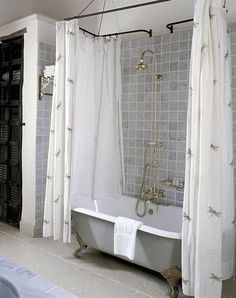 a bath tub sitting under a bathroom window next to a curtained shower stall and toilet