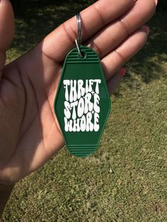 a hand holding a green tag with the words thrift store rhode printed on it