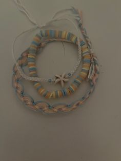 three bracelets with seashells and starfish on them hanging from the wall