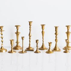 several brass candlesticks lined up on a white surface