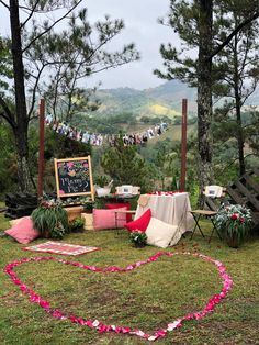 a heart - shaped sign in the middle of a grassy area with flowers and decorations