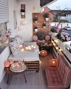 a balcony decorated with candles and potted plants on the roof, surrounded by flowers