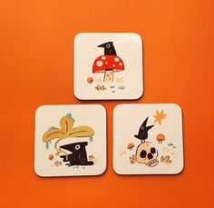 three coasters with cartoon images on them sitting on an orange surface in the shape of mushrooms