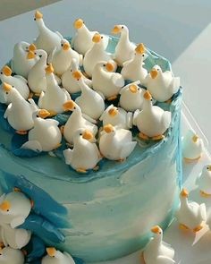 a blue and white cake topped with lots of little ducks on it's side