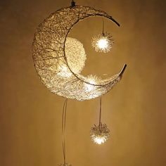 an artistic mobile made out of wire and string with stars hanging from the moon's side