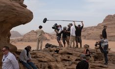 a group of people standing on top of a rocky hillside next to a rock formation