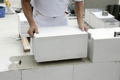 a man in white shirt standing next to a block of cement on top of a building