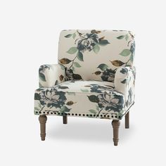 an upholstered chair with floral fabric and nail - tipped wooden legs, against a white background