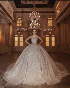 a woman in a wedding dress standing in a room with chandeliers on the ceiling