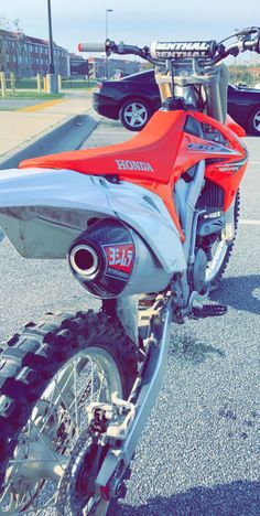 an orange and white dirt bike parked in a parking lot