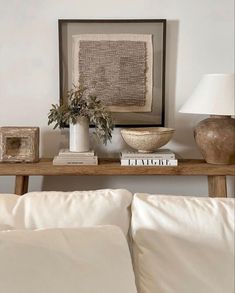 a table with two vases and books on top of it next to a lamp