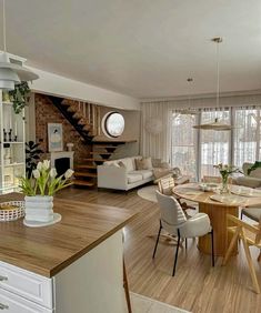 a living room filled with furniture next to a kitchen and dining room table in front of a spiral staircase