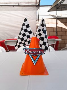 an orange cone sitting on top of a white table covered in checkered flag flags