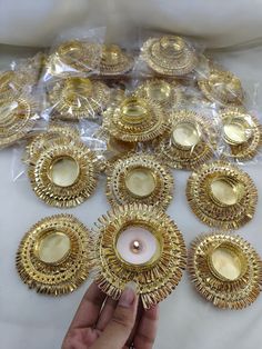 a person holding a lit candle in front of some gold plated objects on a table