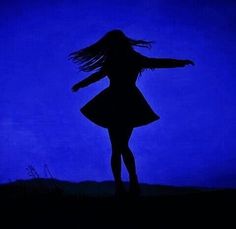 a woman standing in the dark with her arms spread out and hair blowing in the wind