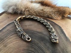 a close up of a metal bracelet on top of a piece of wood with fur