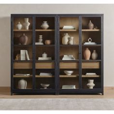 an open bookcase with vases and books on the shelves in front of it