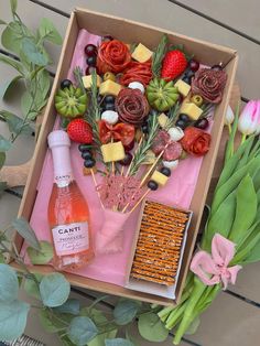 a box filled with flowers and fruit on top of a wooden table next to wine bottles