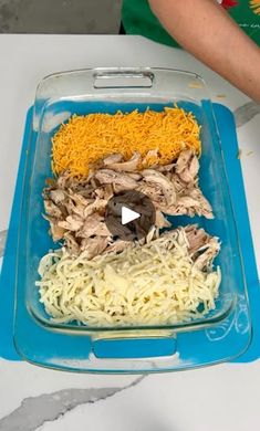 a person holding a tray with noodles and meat in it on a white table top