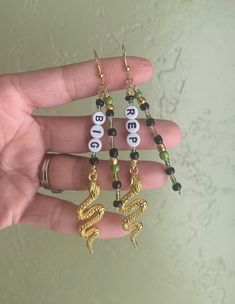 a person is holding three different earrings in their hand with the word bead on them