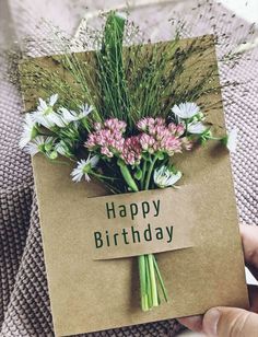 a person holding a card with flowers in it that says happy birthday on the front