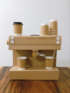 there is a cardboard coffee machine with cups on it